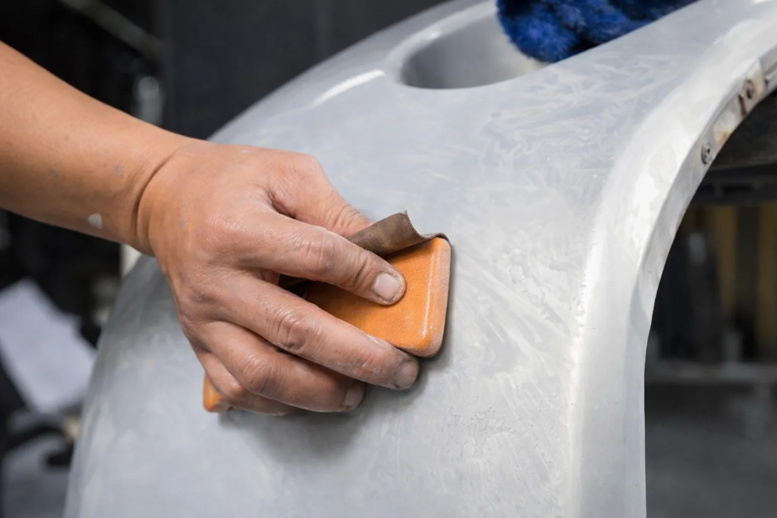 Person sanding a surface with an orange sanding tool