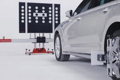 Silver car undergoing alignment in a workshop