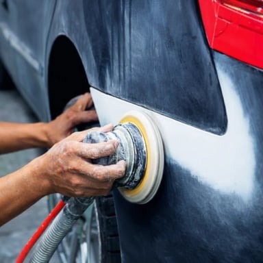 A mechanic polishing a car's surface.
