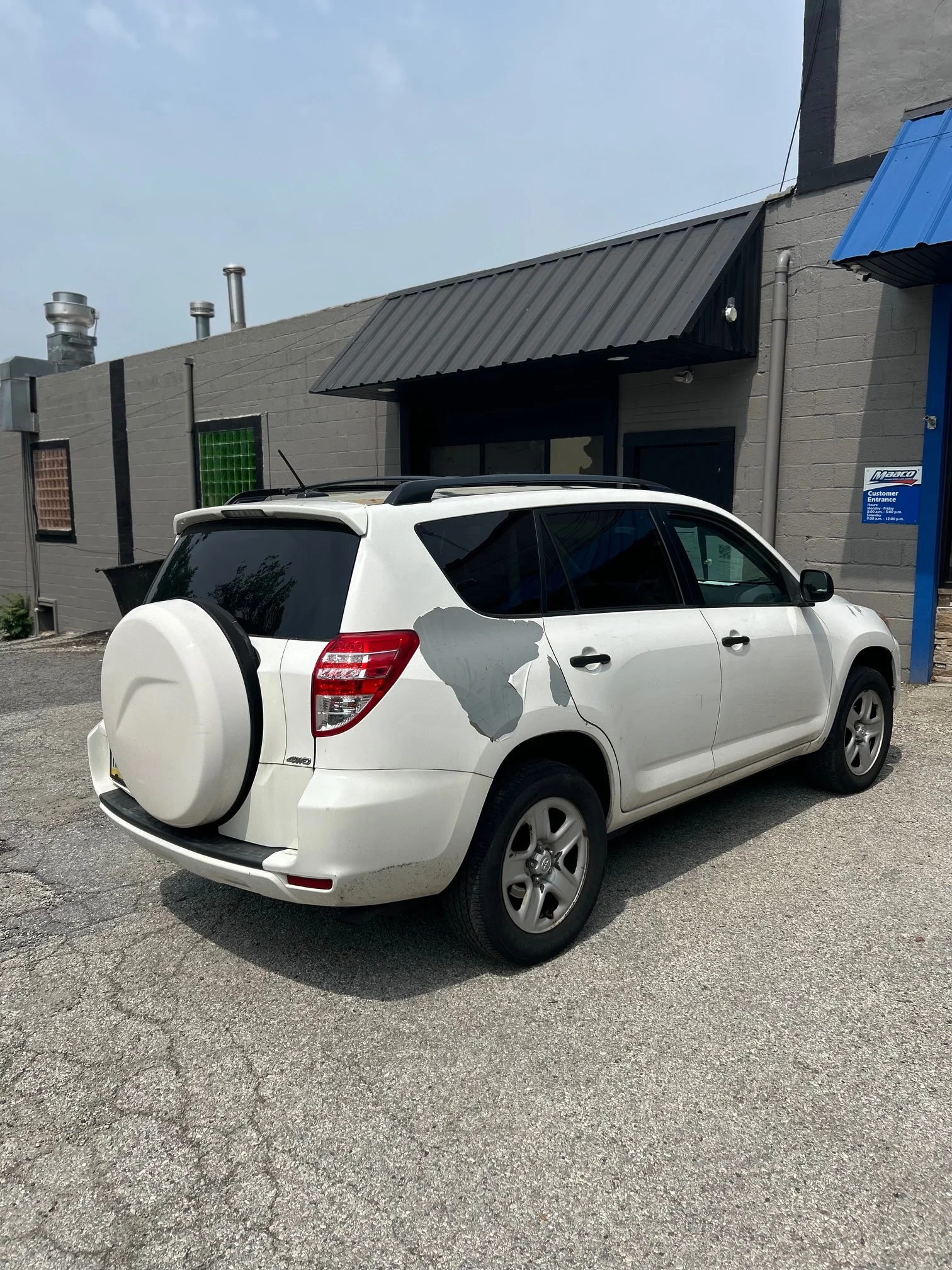 A white SUV parked against a gray wall.